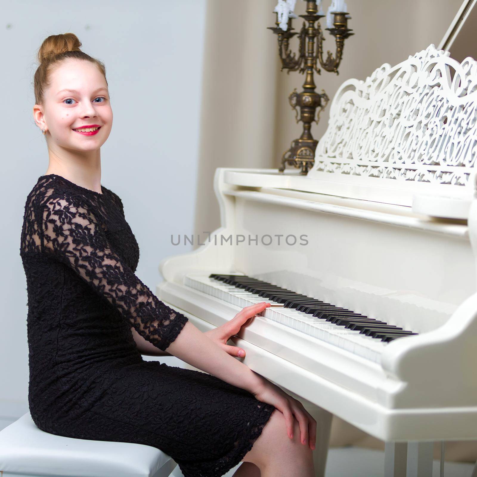 Beautiful little girl near a white grand piano. The concept of education and school, children's creativity.