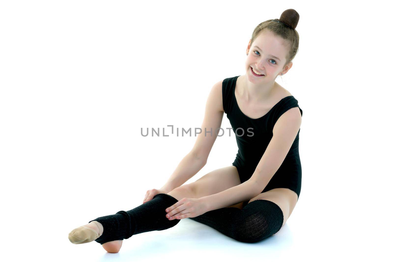 Girl gymnast puts on her leg black leggings. Sport concept, isolated on white background.