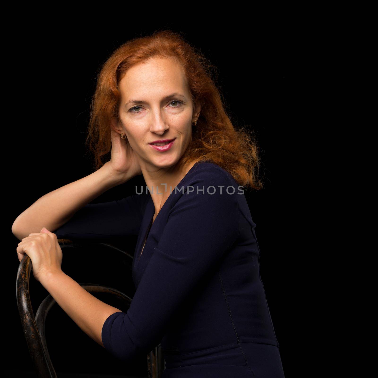 Fashion, artistic portrait of a beautiful red-haired model girl, with long hair on a black background.