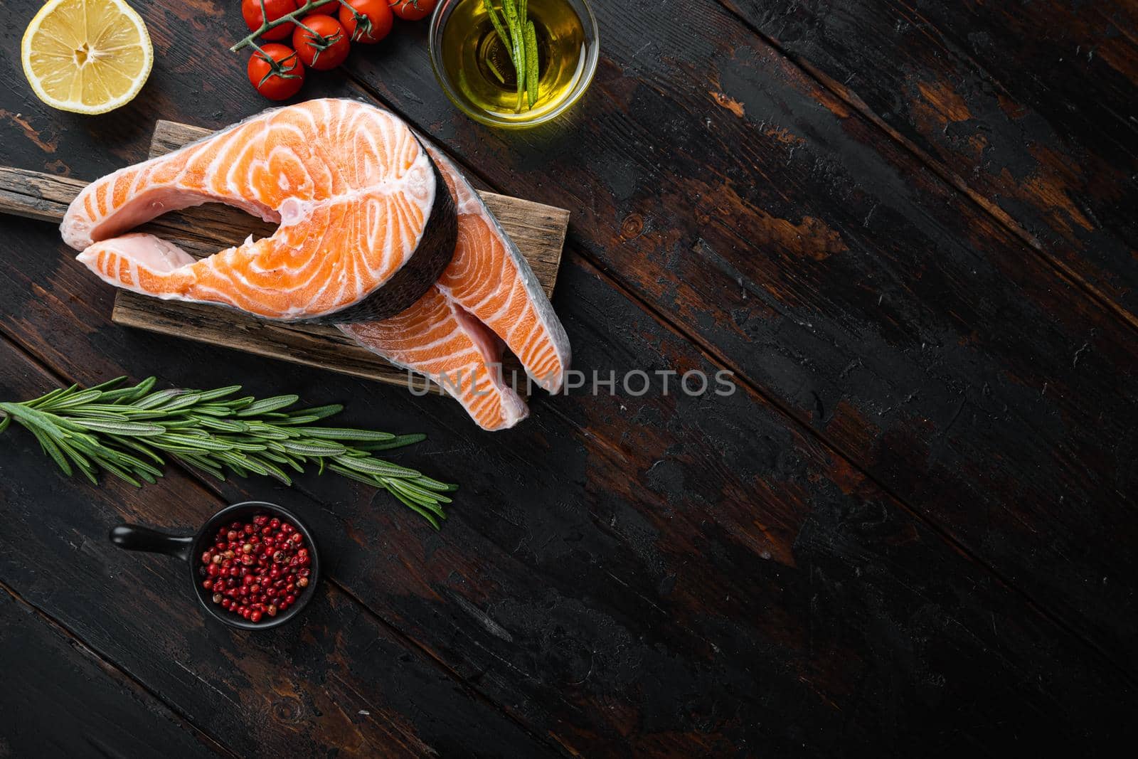 Fesh raw trout fillet with herbs, on old wooden table, top view with space for text.