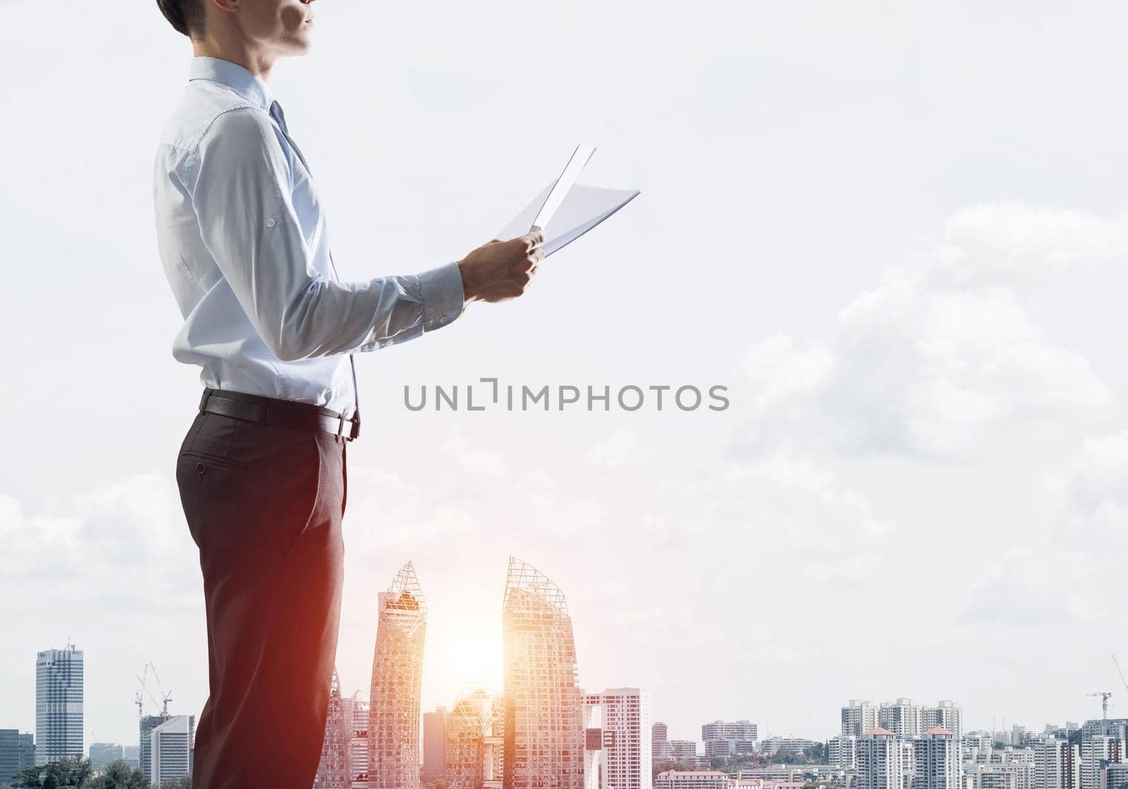 Young elegant businessman with papers in hands looking away