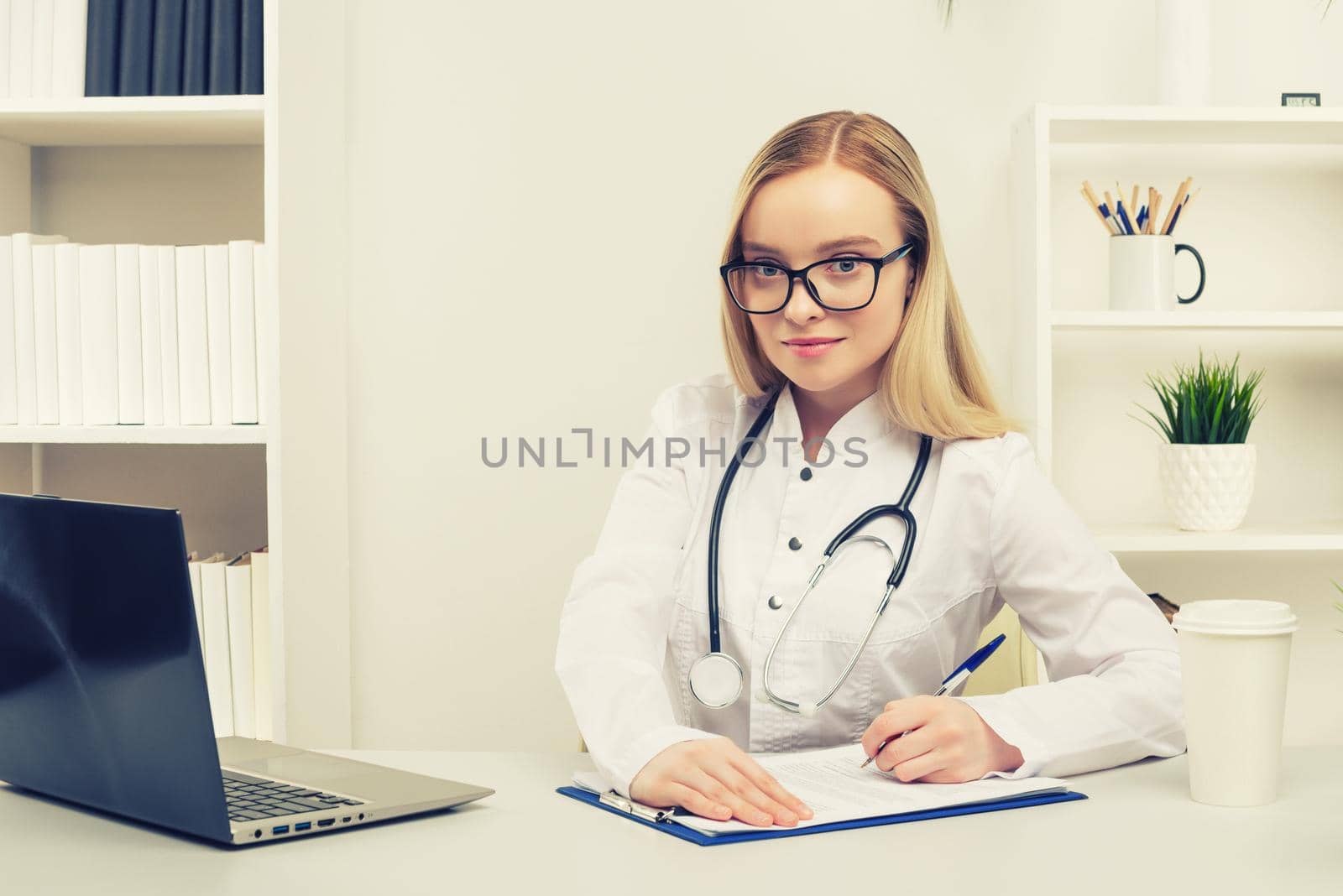 Young beautiful doctor woman working happy and smile in hospital, sitting on table, medical concept, toned