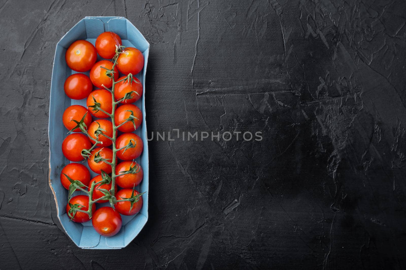Red ripe cherry tomatoes, on black background with copy space for text