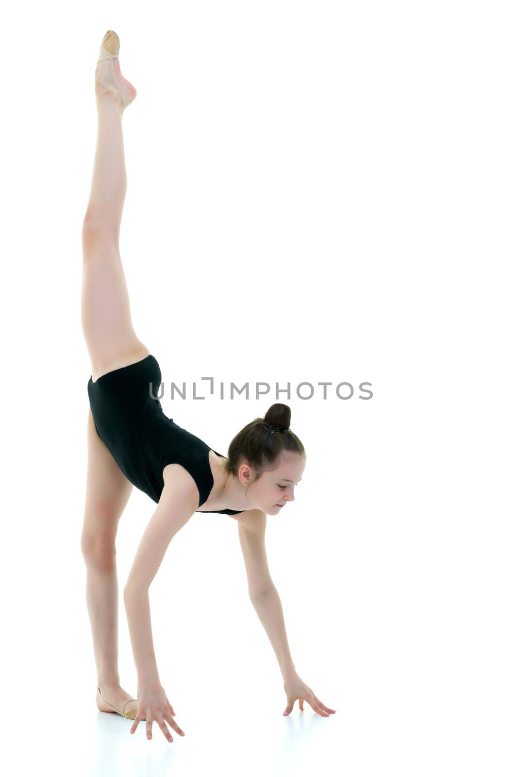 A girl gymnast performs an acrobatic element on the floor. The concept of childhood, sport, healthy lifestyle. Isolated on white background.