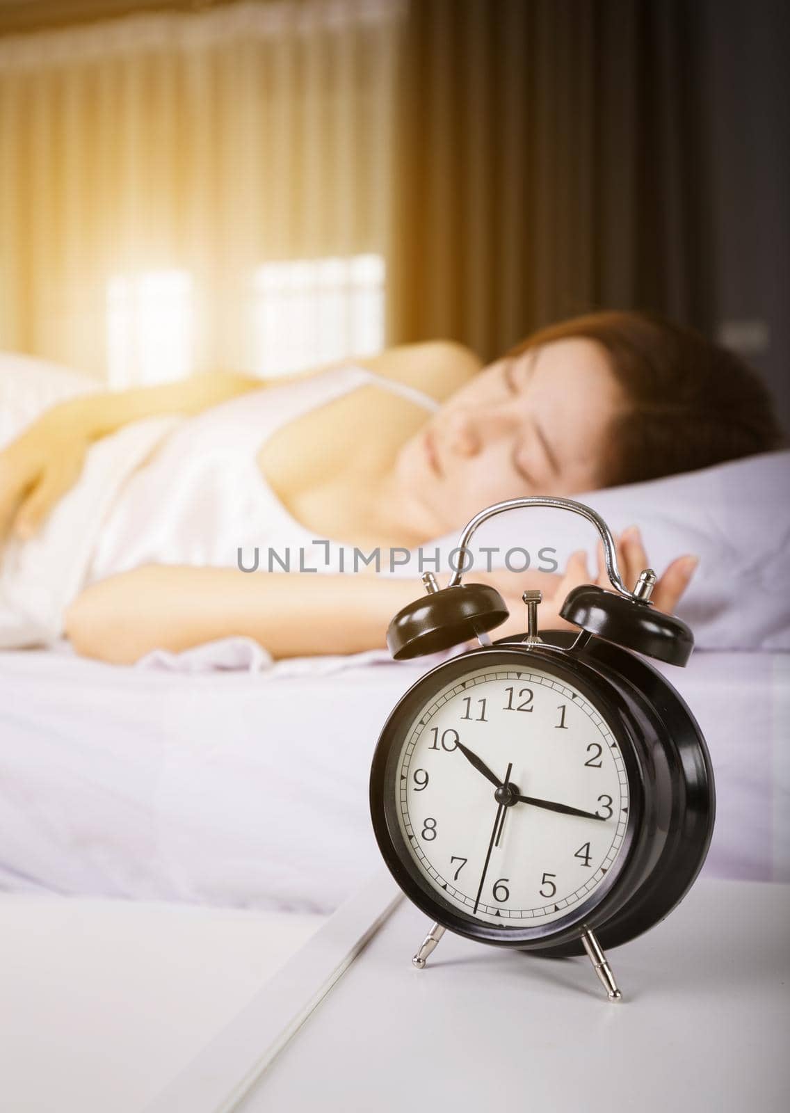 clock show 10 am. and woman sleeping on bed with sunlight in the morning