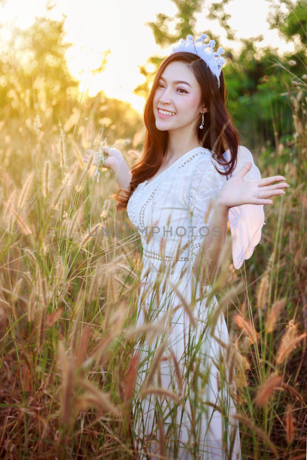 beautiful angel woman in a grass field with sunlight