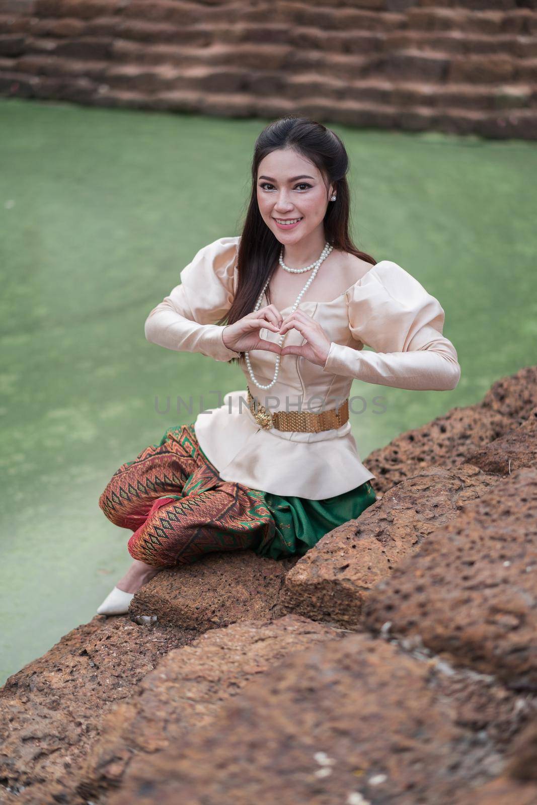 happy beautiful woman in Thai traditional dress near the pond