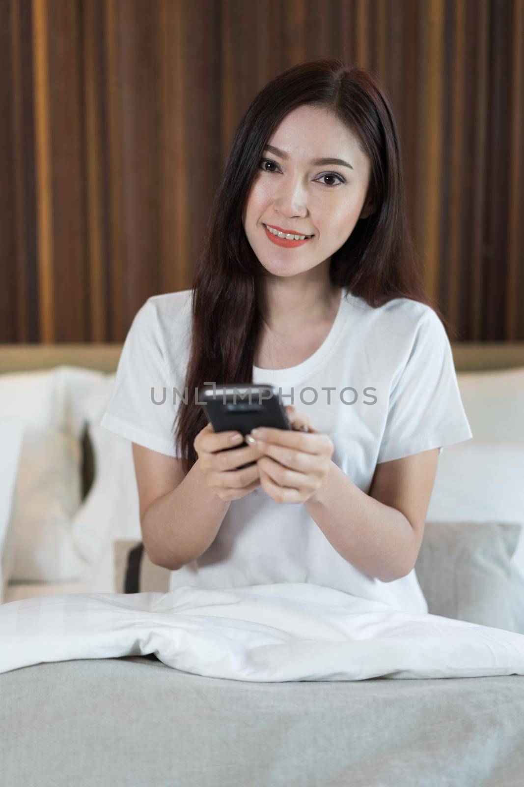 woman using her smartphone on a bed