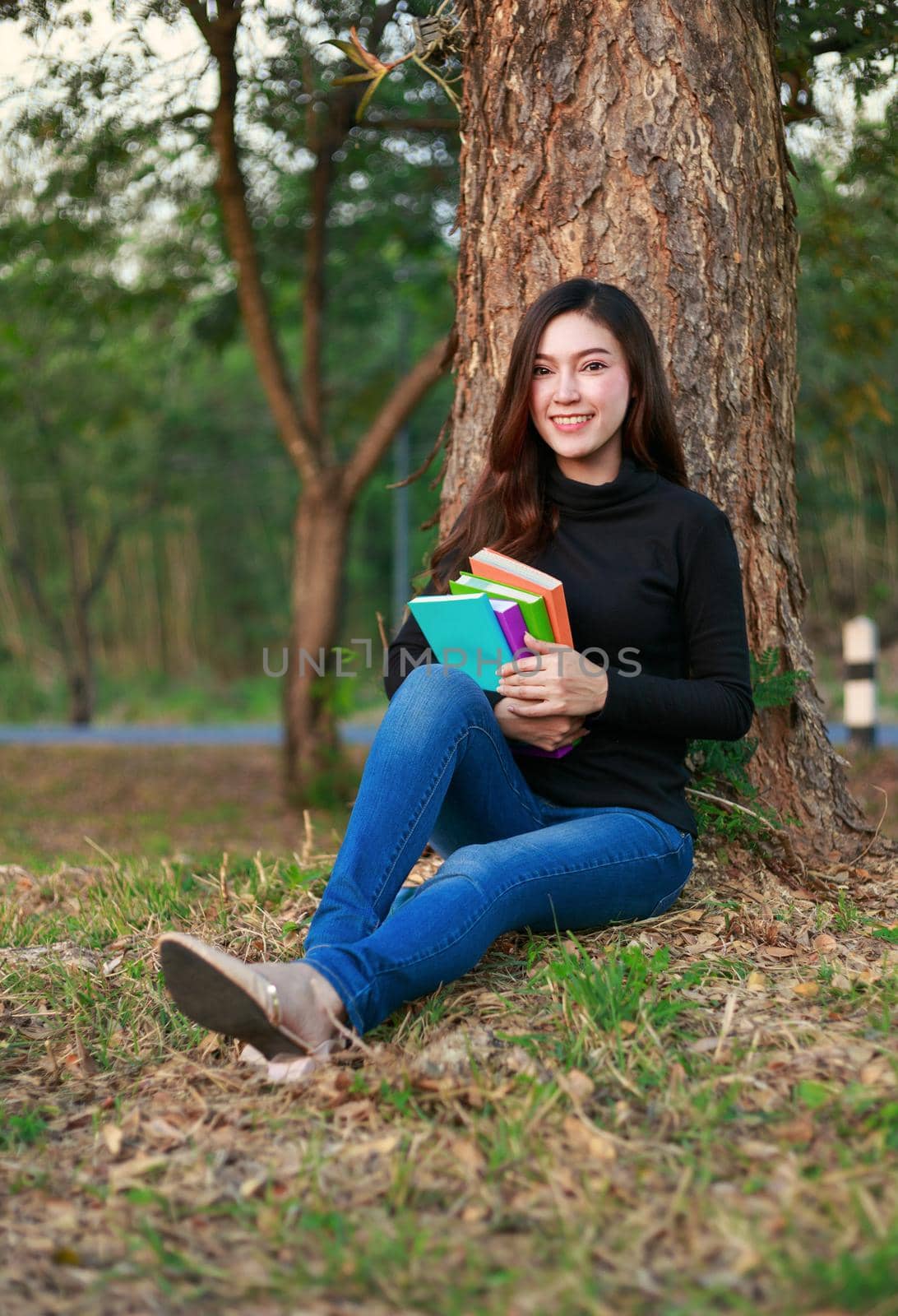 young woman sitting and holding a book in park by geargodz
