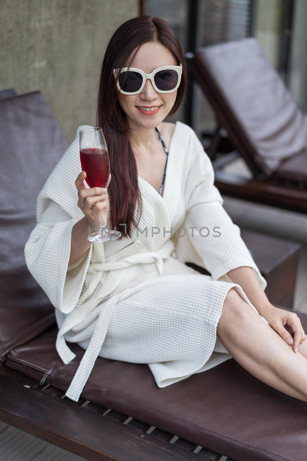 woman clothed bathrobe sitting on deckchair in pool by geargodz