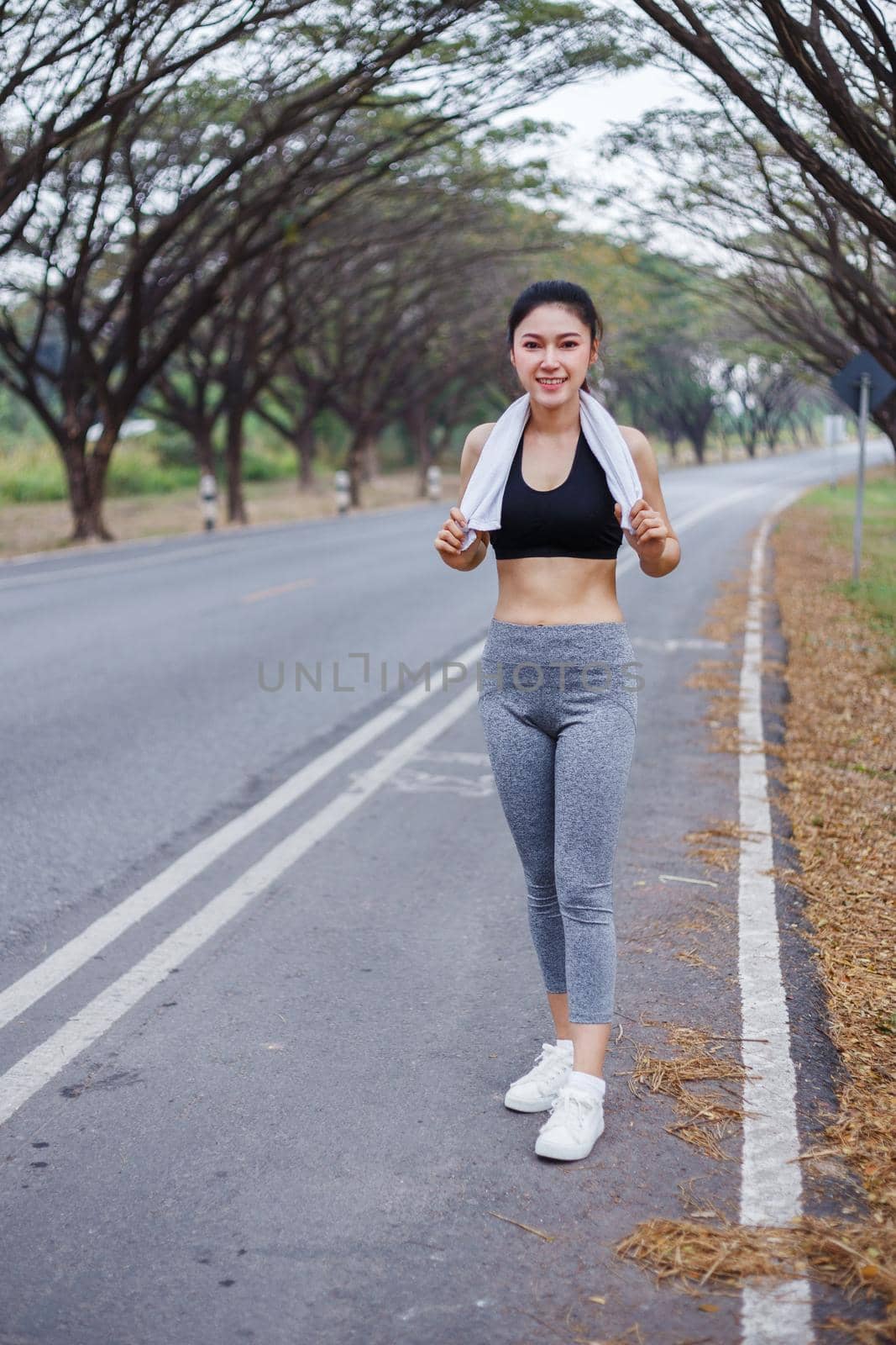 young sporty woman with white towel resting after workout sport exercises outdoors at park by geargodz