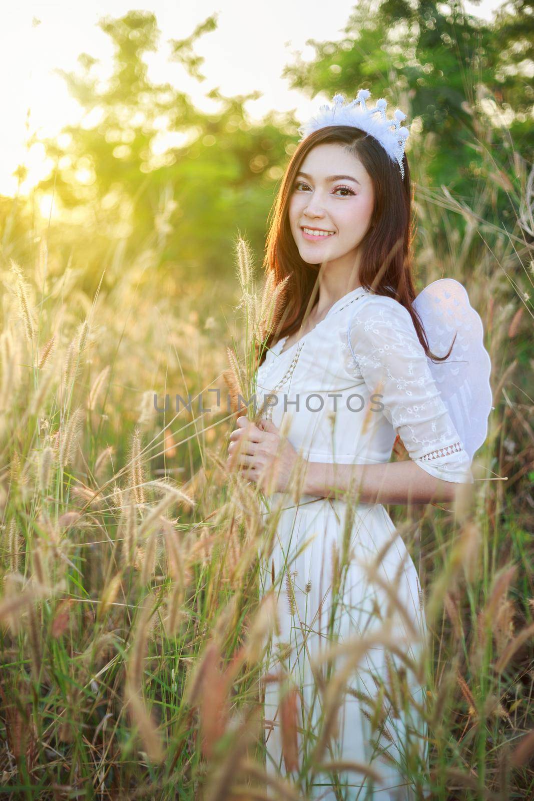 beautiful angel woman in a grass field with sunlight