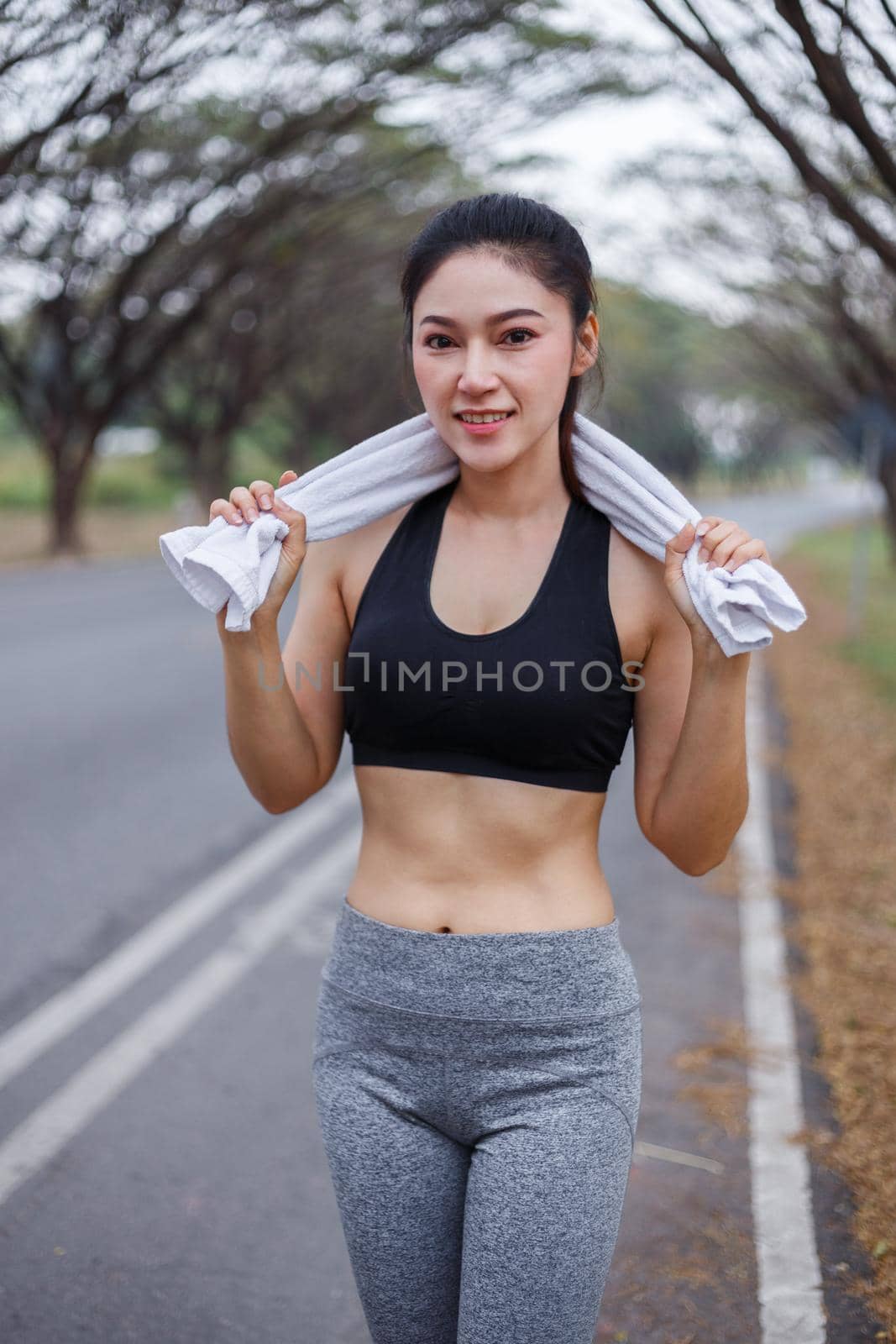 young sporty woman with white towel resting after workout sport exercises outdoors at the park