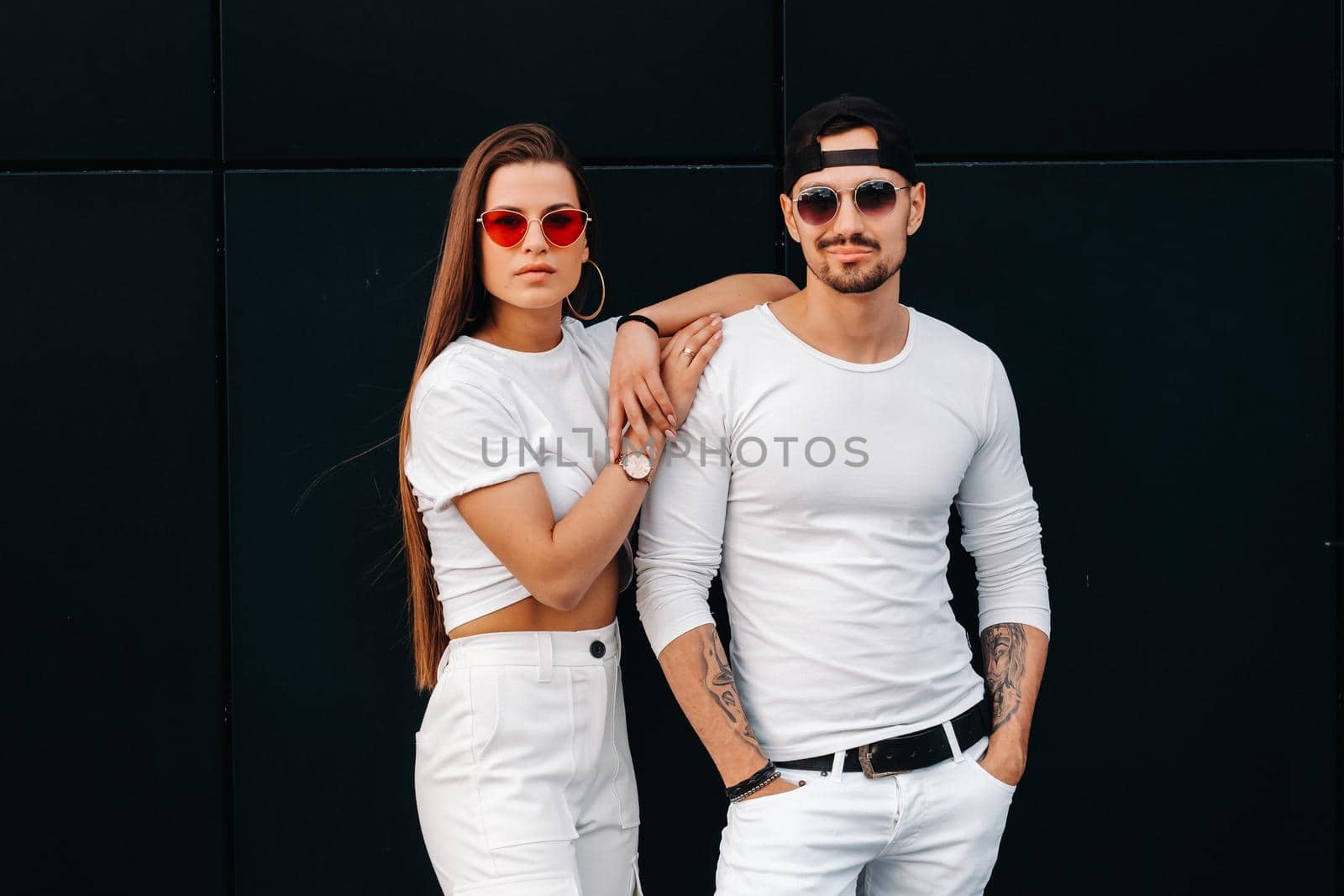 A beautiful couple in love in white stylish clothes are walking in the city by Lobachad