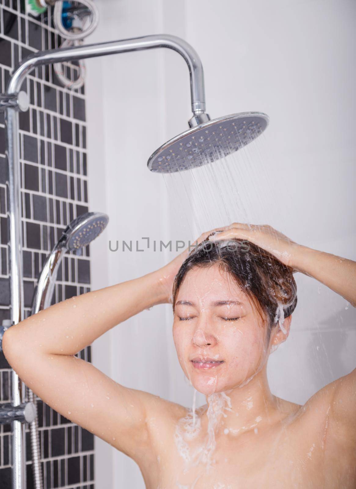woman washing her head and hair in the rain shower by shampoo