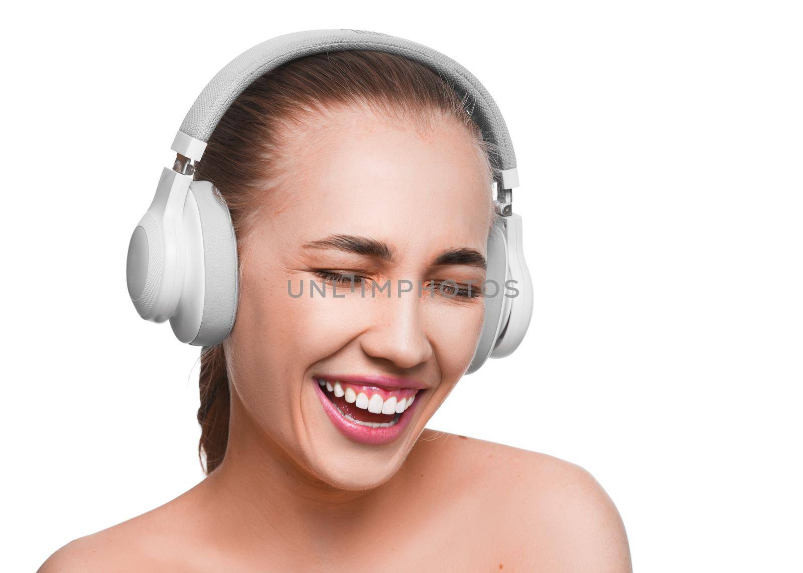 Happy smiling woman with closed eyes in headphones over white background.