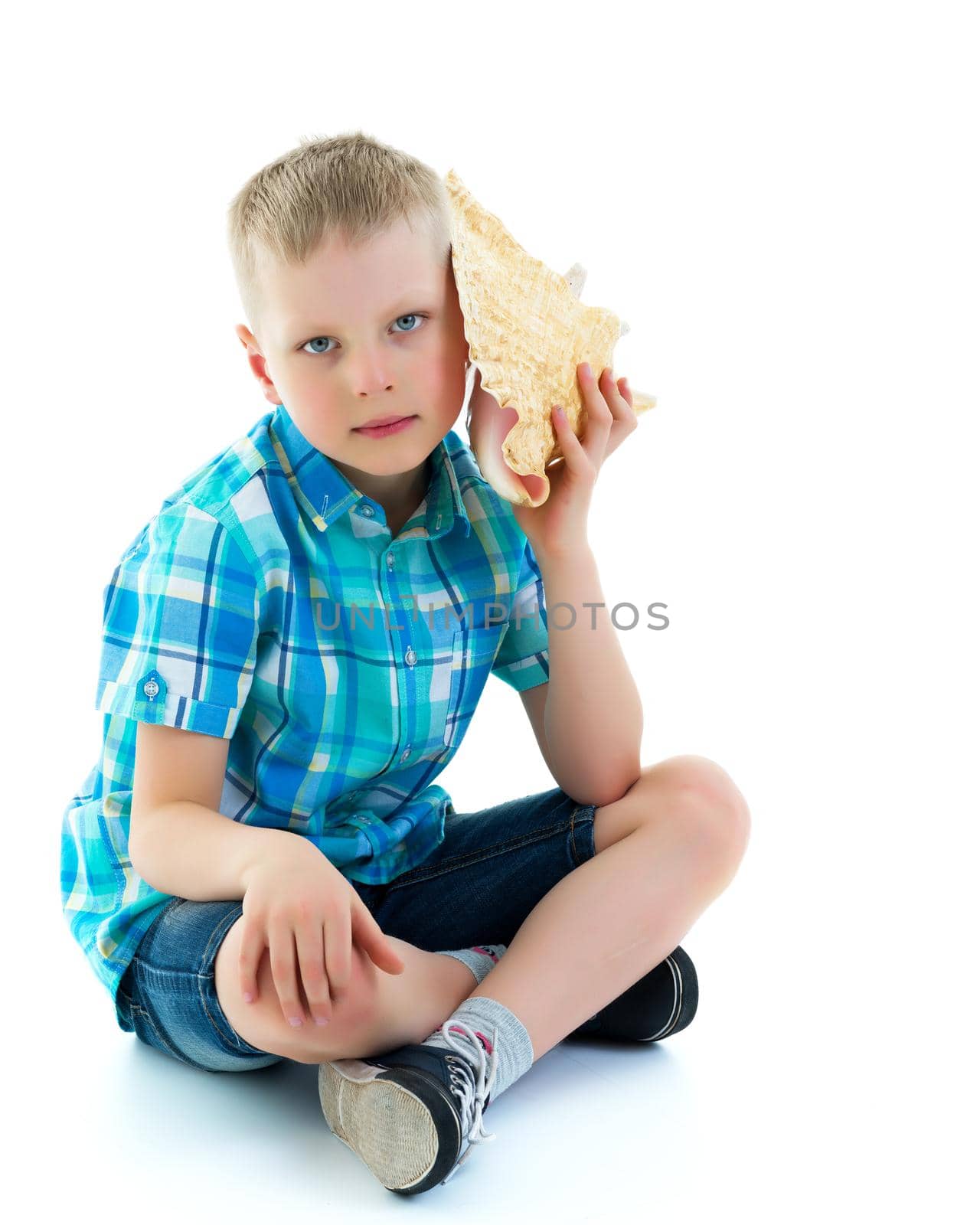A cute little boy with a sea shell. The concept of a family vacation at sea, advertising of summer tourism. Isolated on white background.