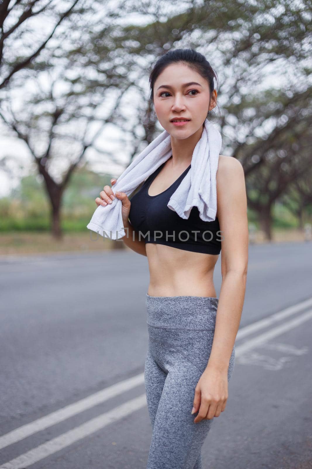 young sporty woman with white towel resting after workout sport exercises outdoors at park by geargodz