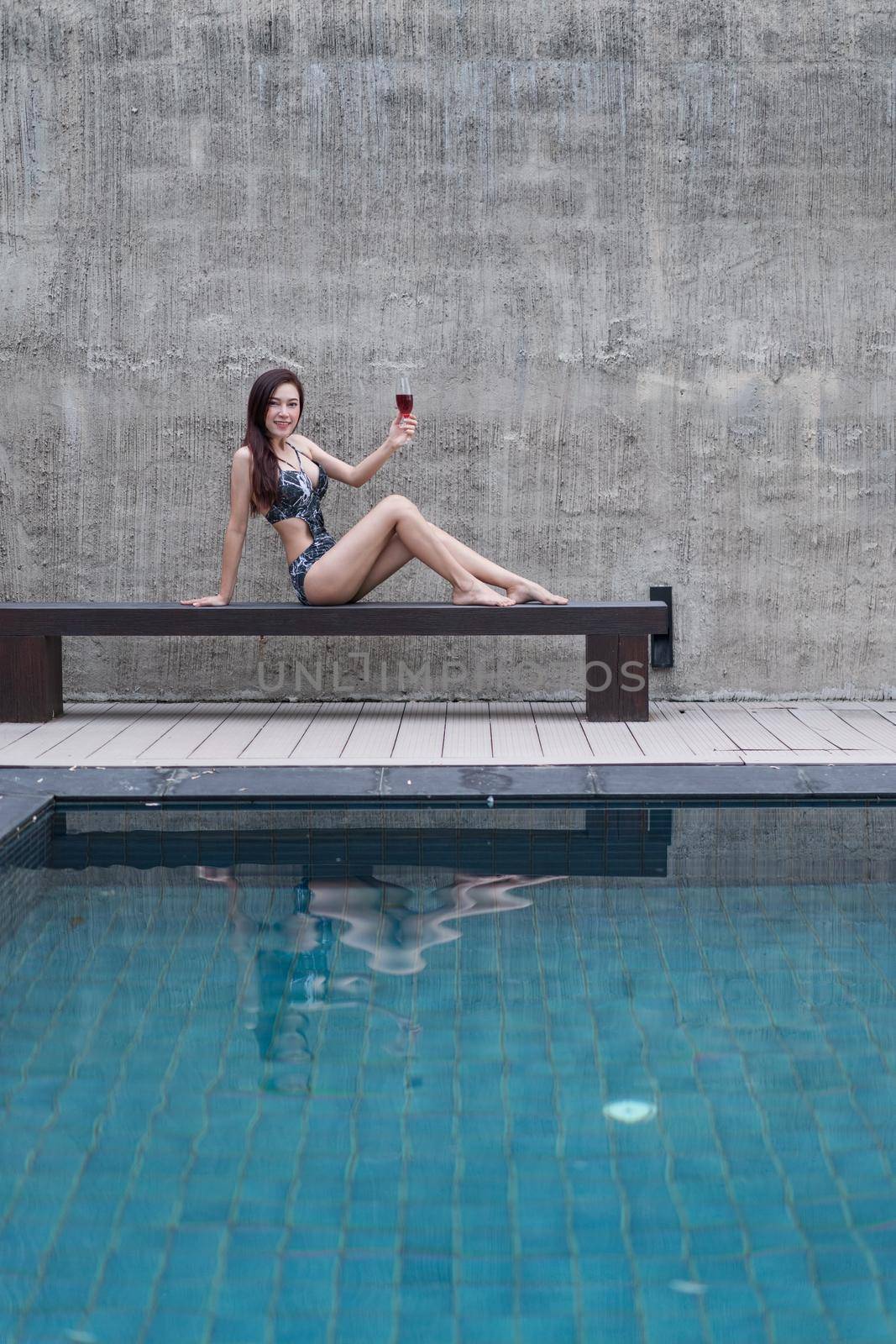 woman on chair and holding a glass in swimming pool by geargodz