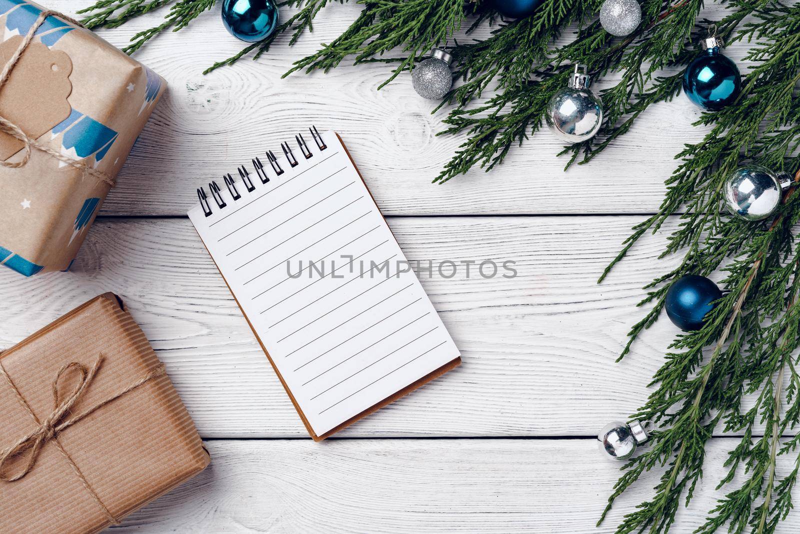 White wooden background with coniferous branches and Christmas decorations, top view