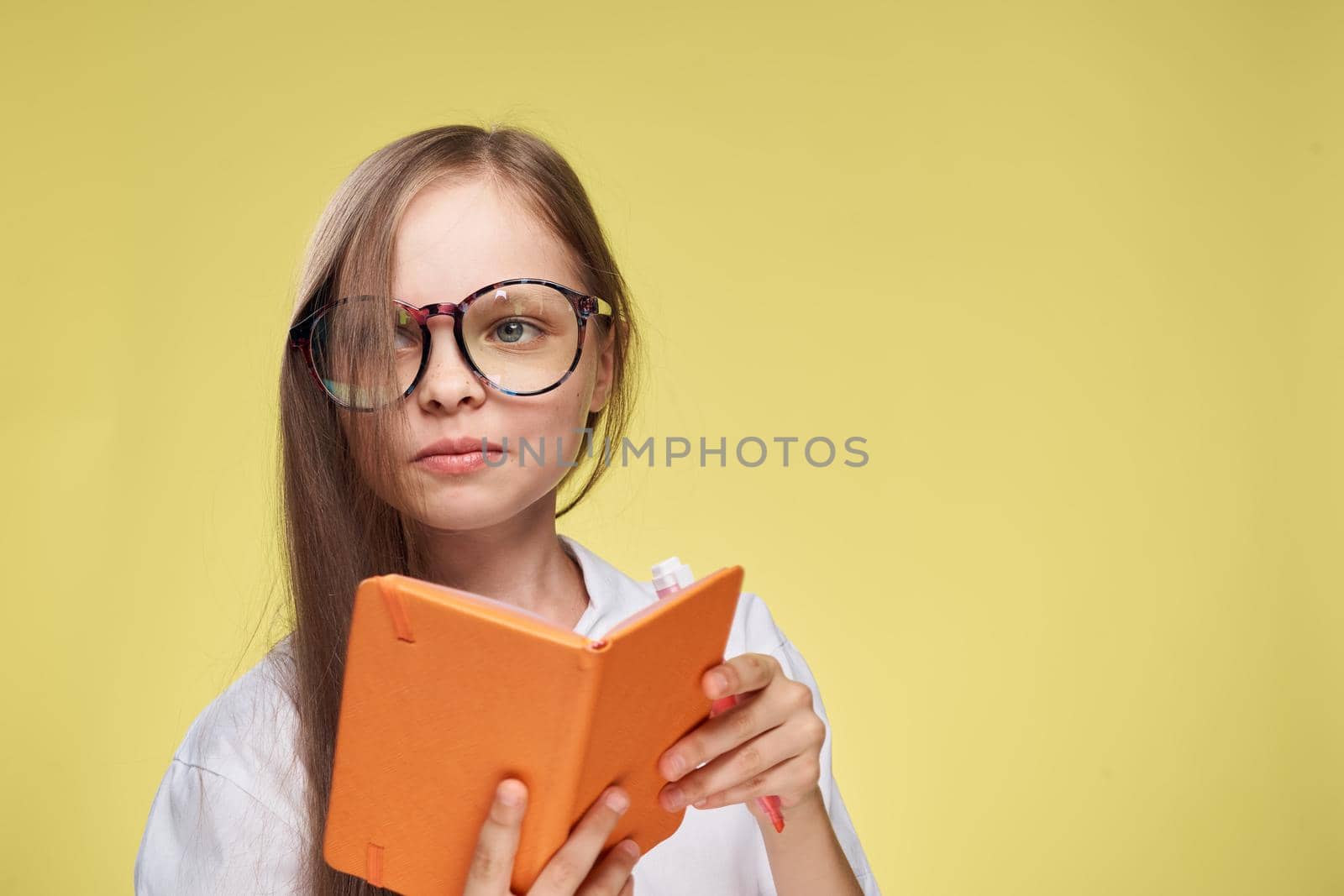 schoolgirl with textbook in hands learning childhood yellow background. High quality photo