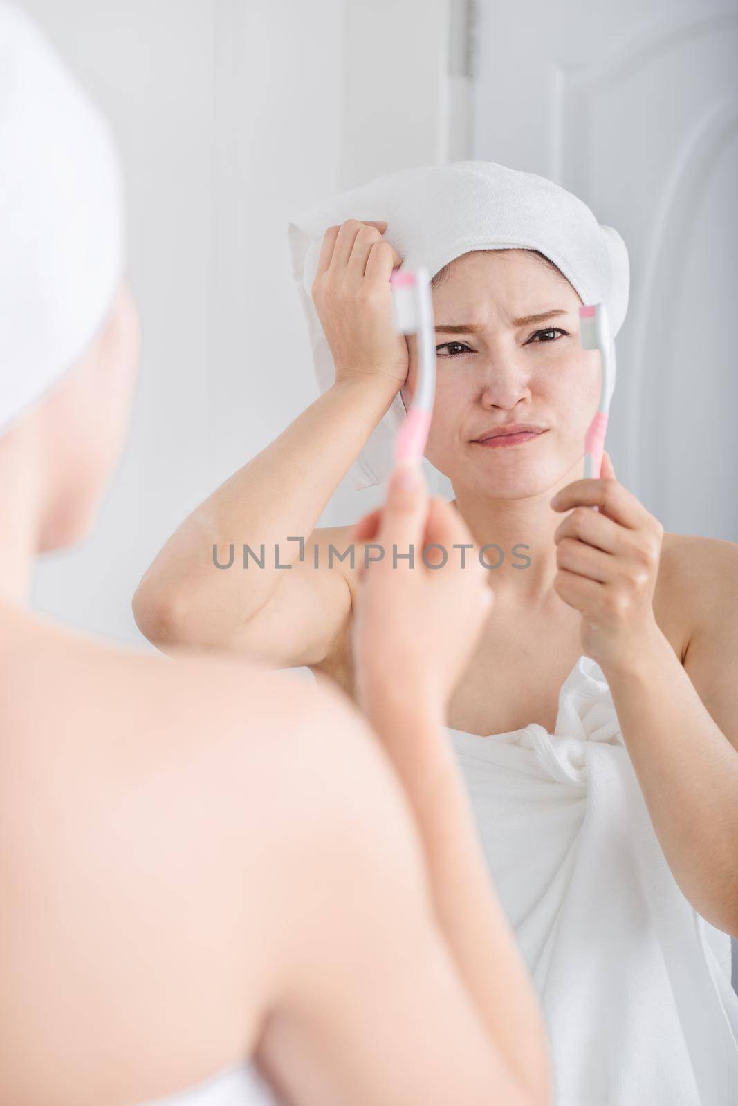 unhappy woman in bath towel brushing teeth with mirror in bathroom by geargodz