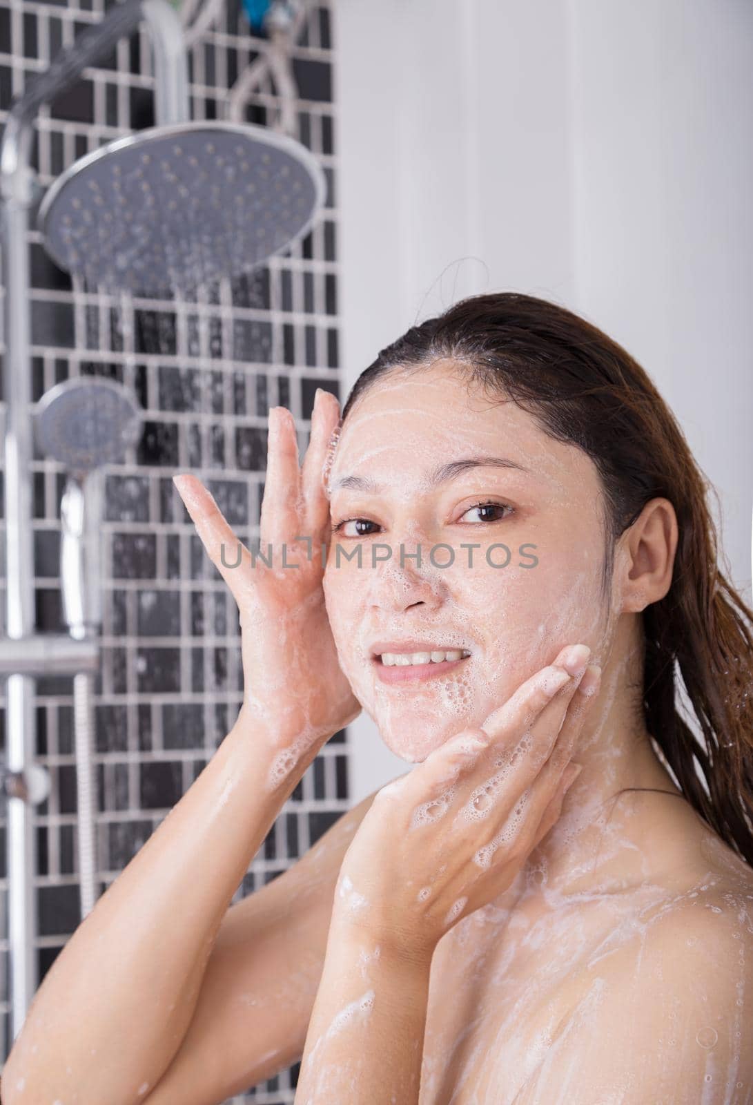 woman washing face in shower foaming in the bathroom