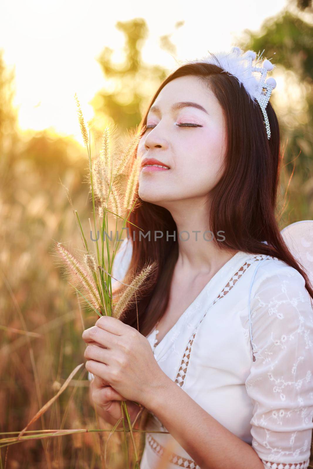 beautiful angel woman in a grass field with sunlight