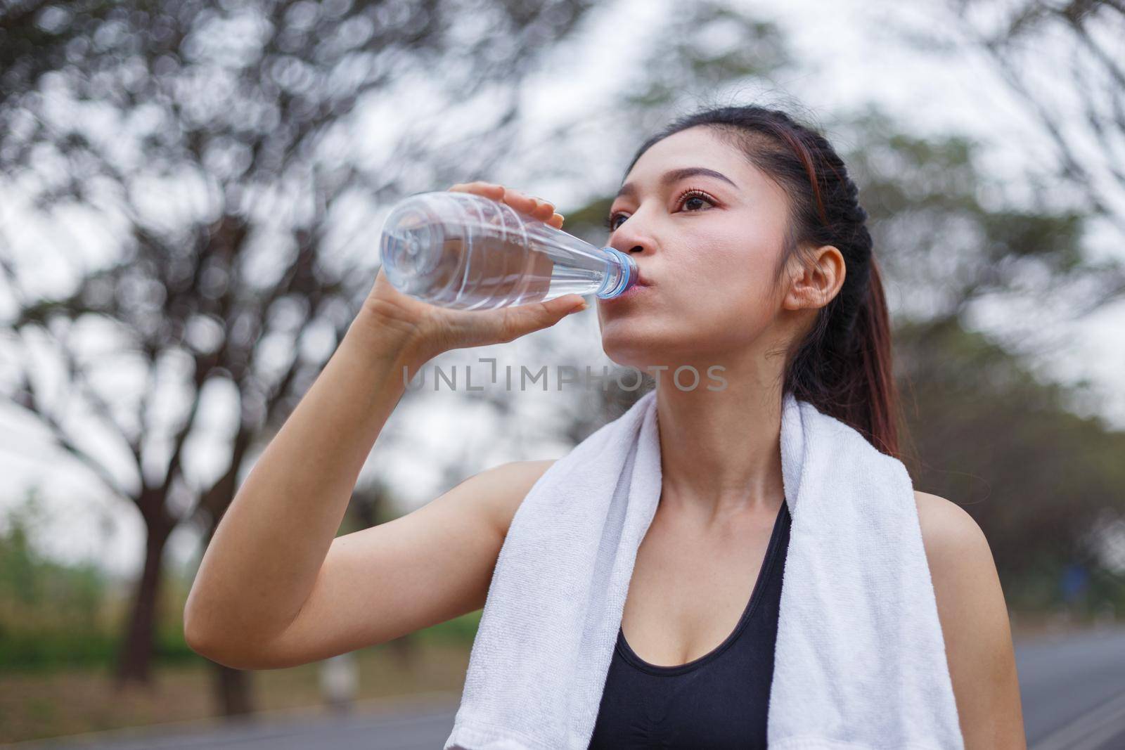 young sporty woman drinking water in the park