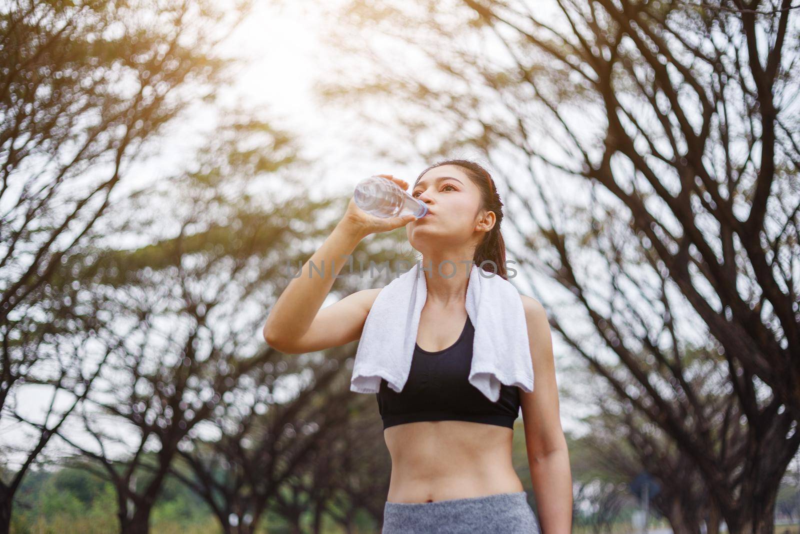 young sporty woman drinking water in the park