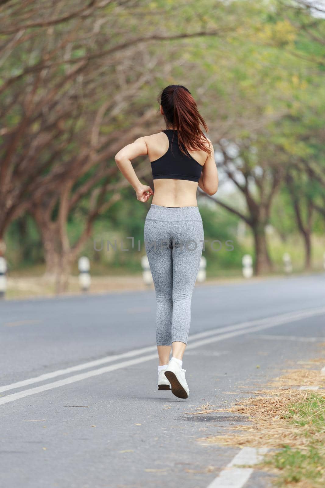 young fitness woman running in park by geargodz