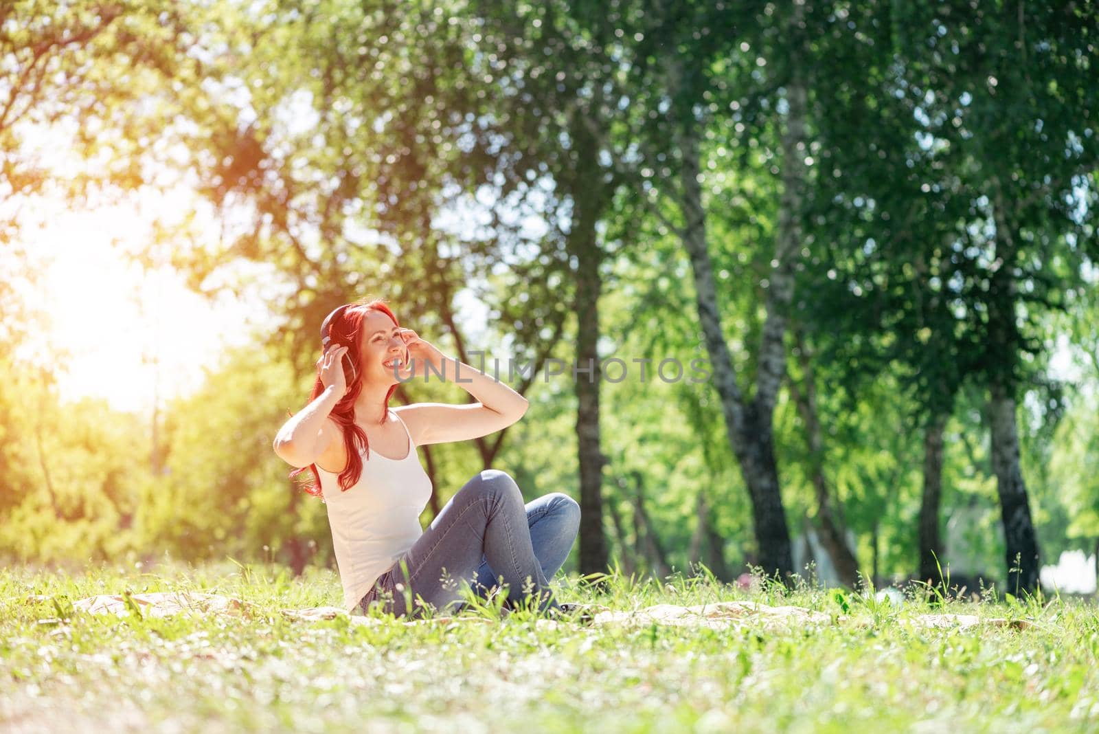 Young attractive woman listens to music in the park. Enjoying music in the park