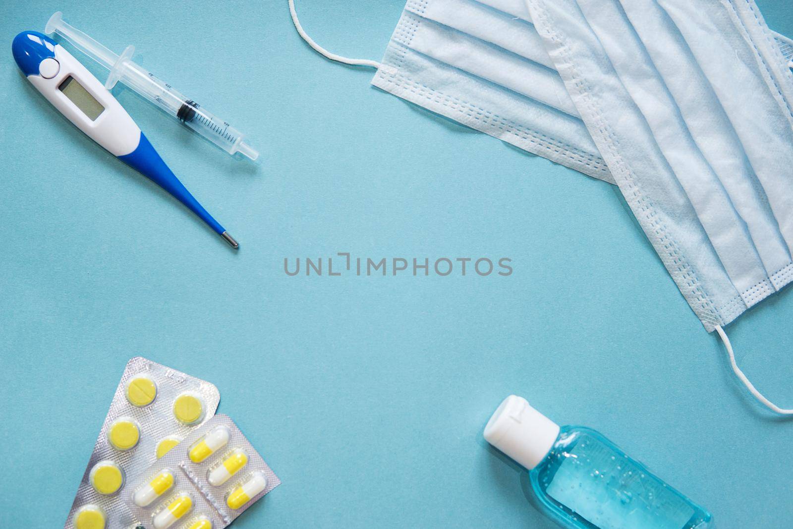 Virus prevention and treatment: wearing masks, hand disinfection, taking antiviral drugs and vitamins. First aid kit with medicines on a blue background.