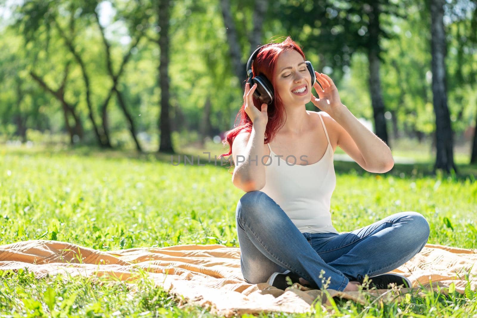 Young attractive woman listens to music in the park. Enjoying music in the park
