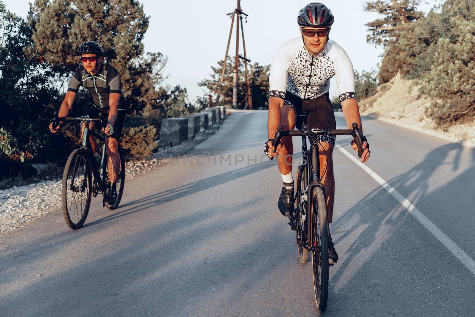 Two professional male cyclists riding their racing bicycles in the morning together on coastal road