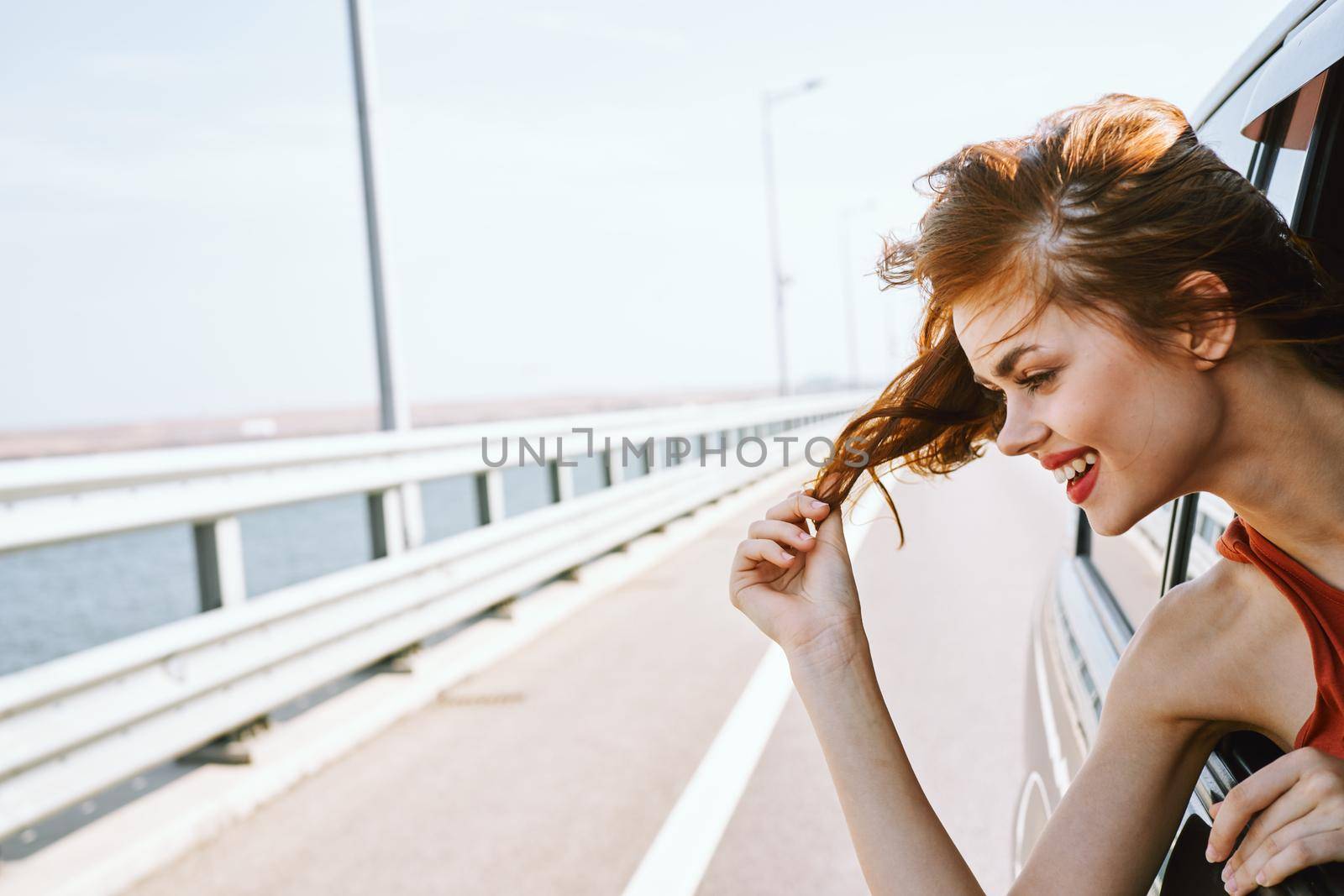 cheerful woman peeking out of the car window trip road travel. High quality photo