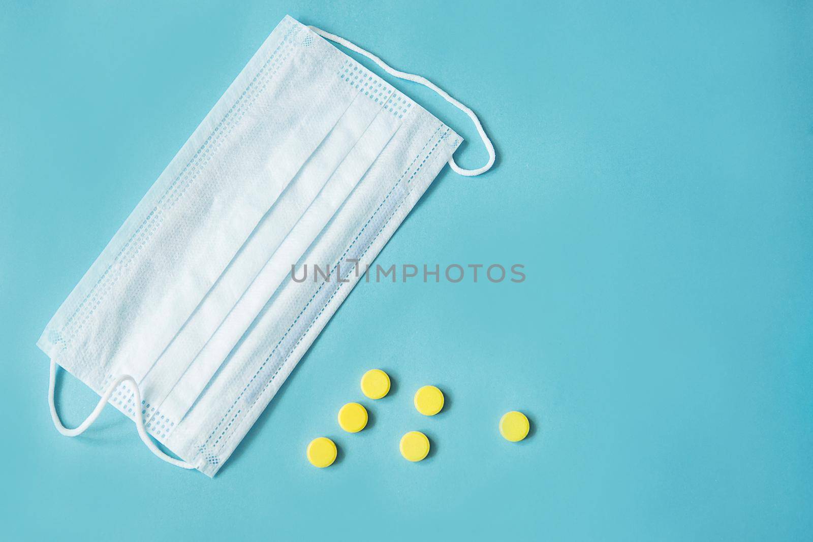 Respiratory mask and medicine in capsules on blue background.Virus prevention and treatment.