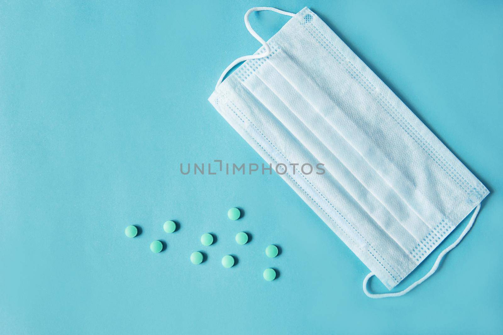 Respiratory mask and medicine in capsules on blue background.Virus prevention and treatment.