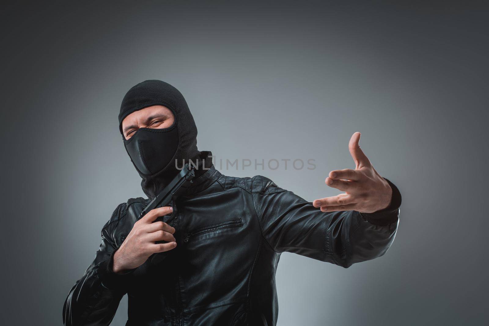 Robber in a mask with a gun, studio shot