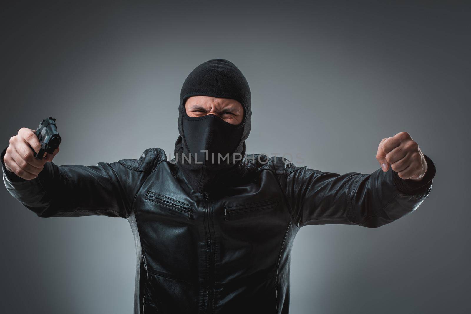 Robber in a mask with a gun, studio shot