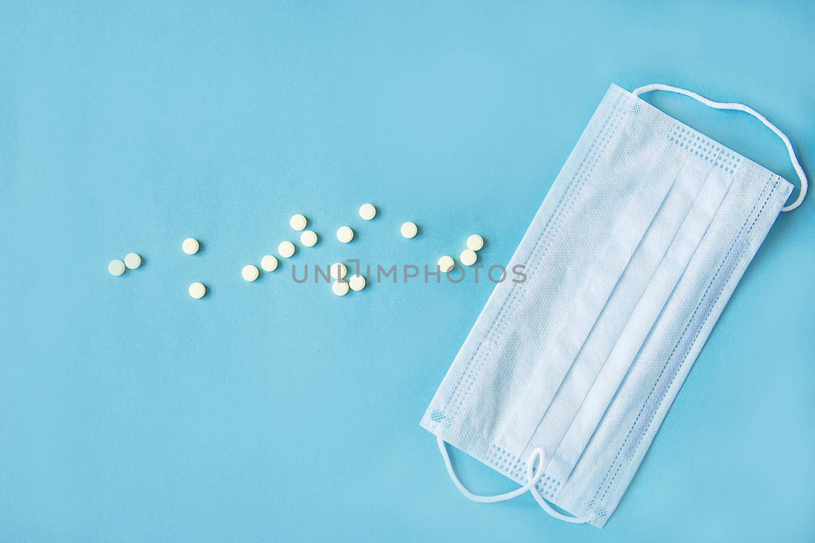 Respiratory mask and medicine in capsules on blue background.Virus prevention and treatment.