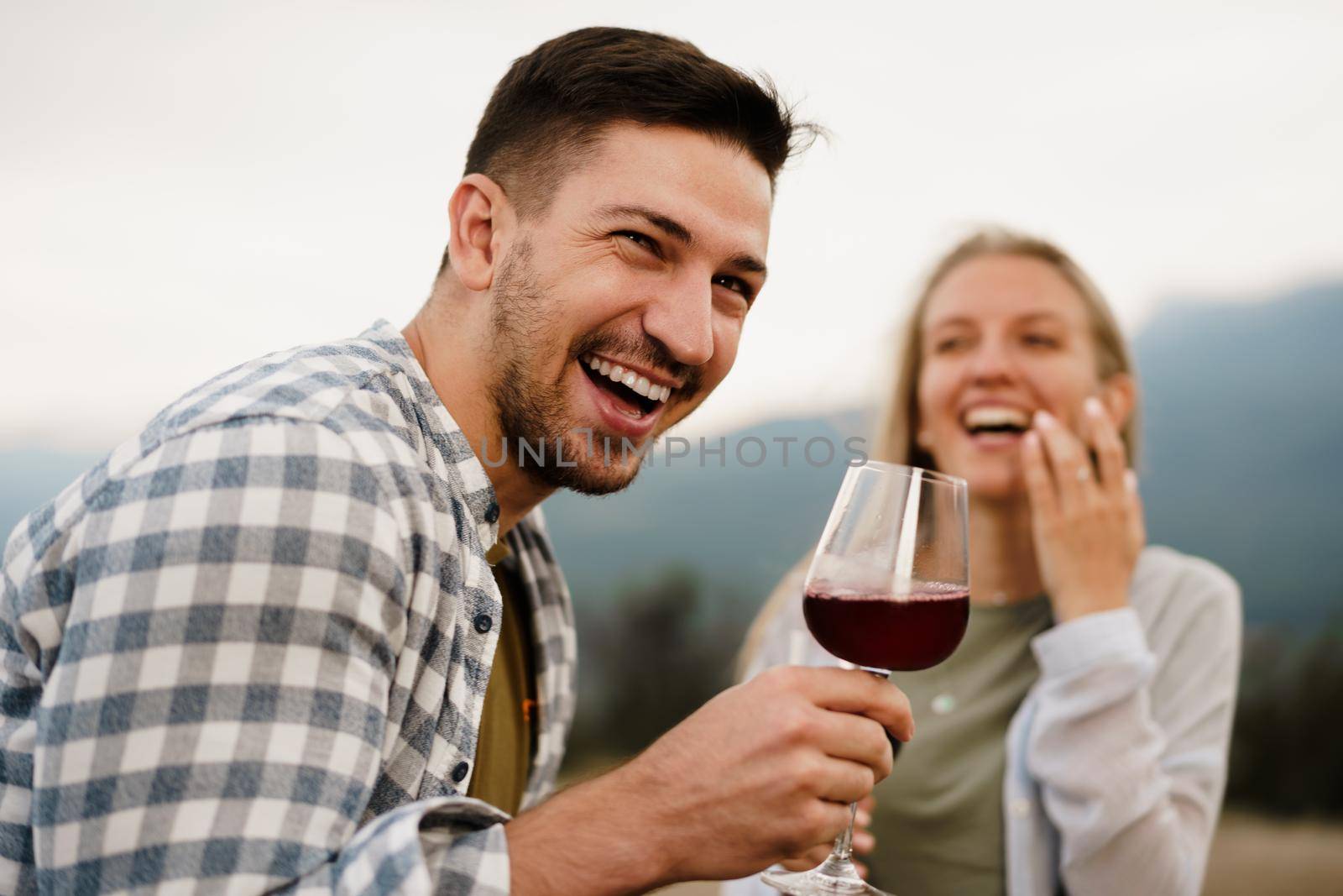Smiling couple toasting wine glasses outdoors in mountains, close up portrait