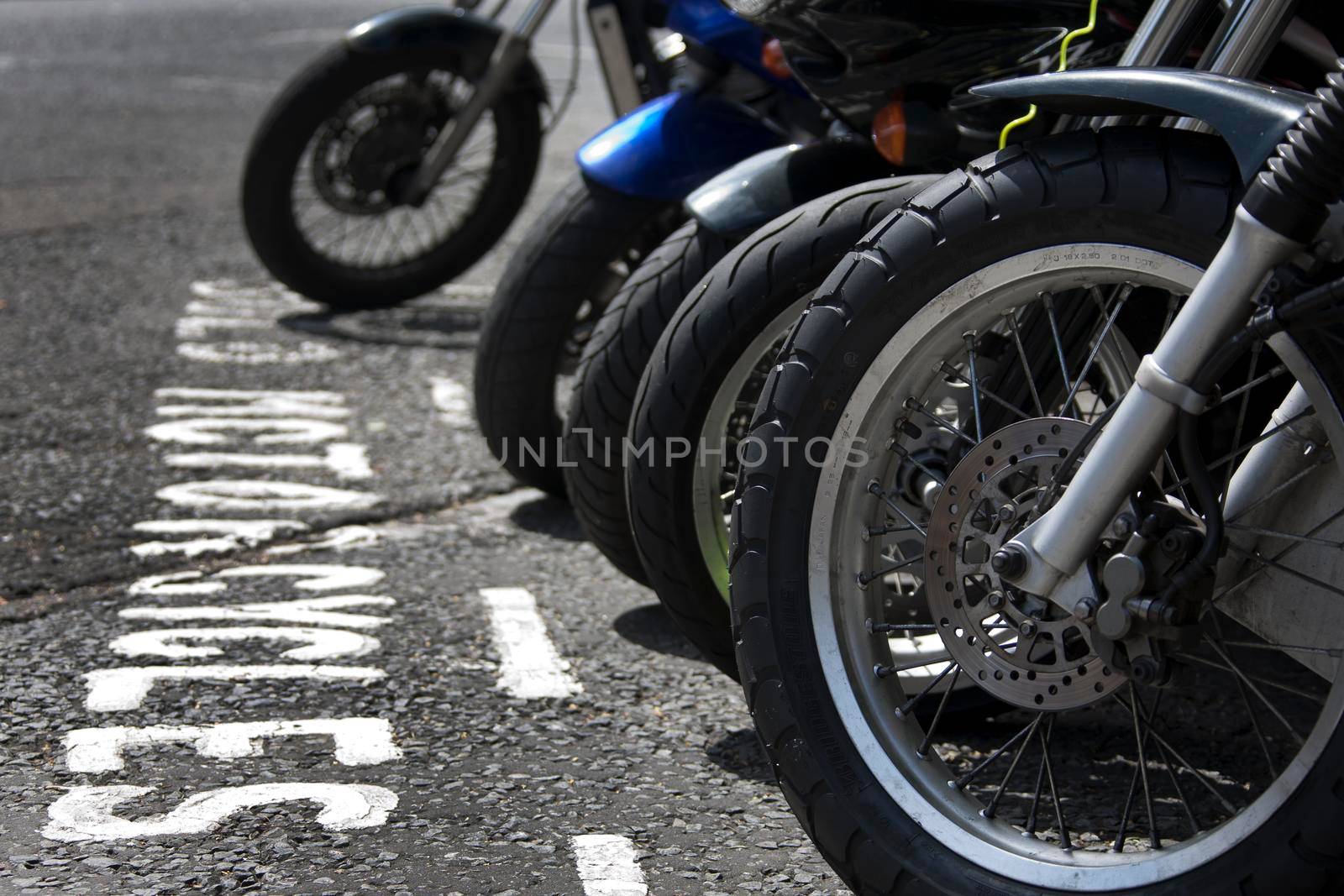 The front wheels of motorcycles parked in a bay
