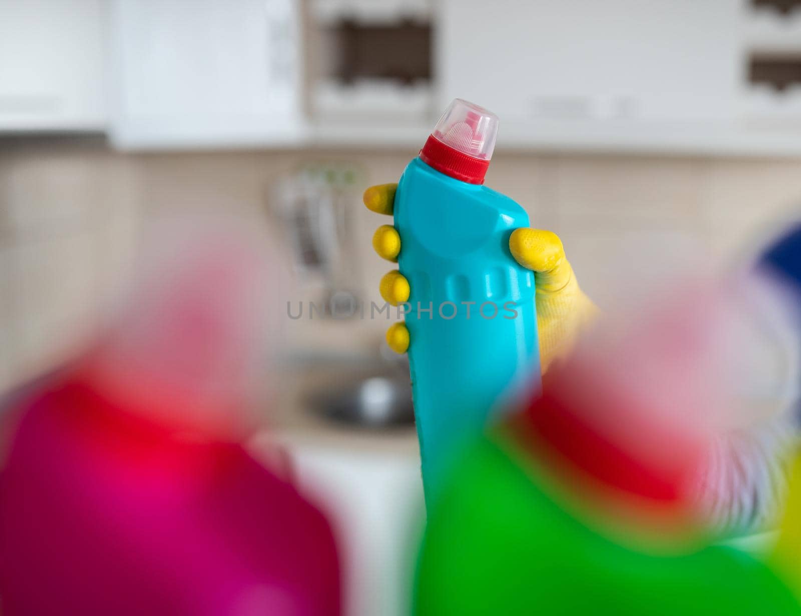 Woman taking bottle with cleaning detergent from shelf in pantry by budabar