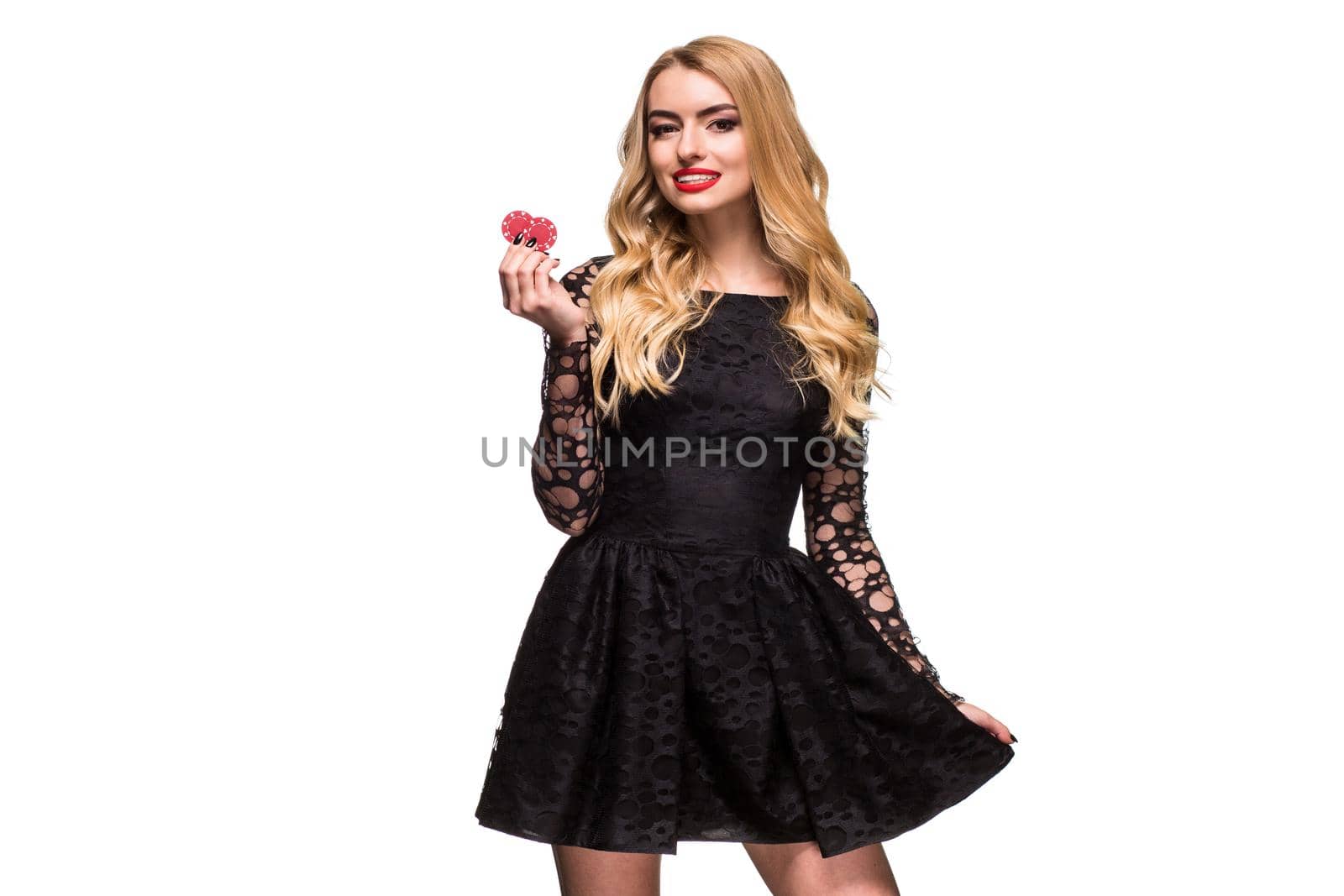Beautiful blonde in a black dress with casino chips in hands isolated on a white background. Poker. Casino. Roulette Blackjack Spin. Caucasian young woman looking at the camera