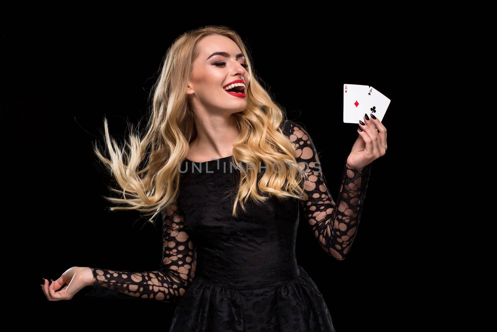 Beautiful young woman in black dress holding two ace of cards in her hand, isolated on black background. Poker. Casino. Roulette Blackjack Spin. Caucasian woman looking at the cards