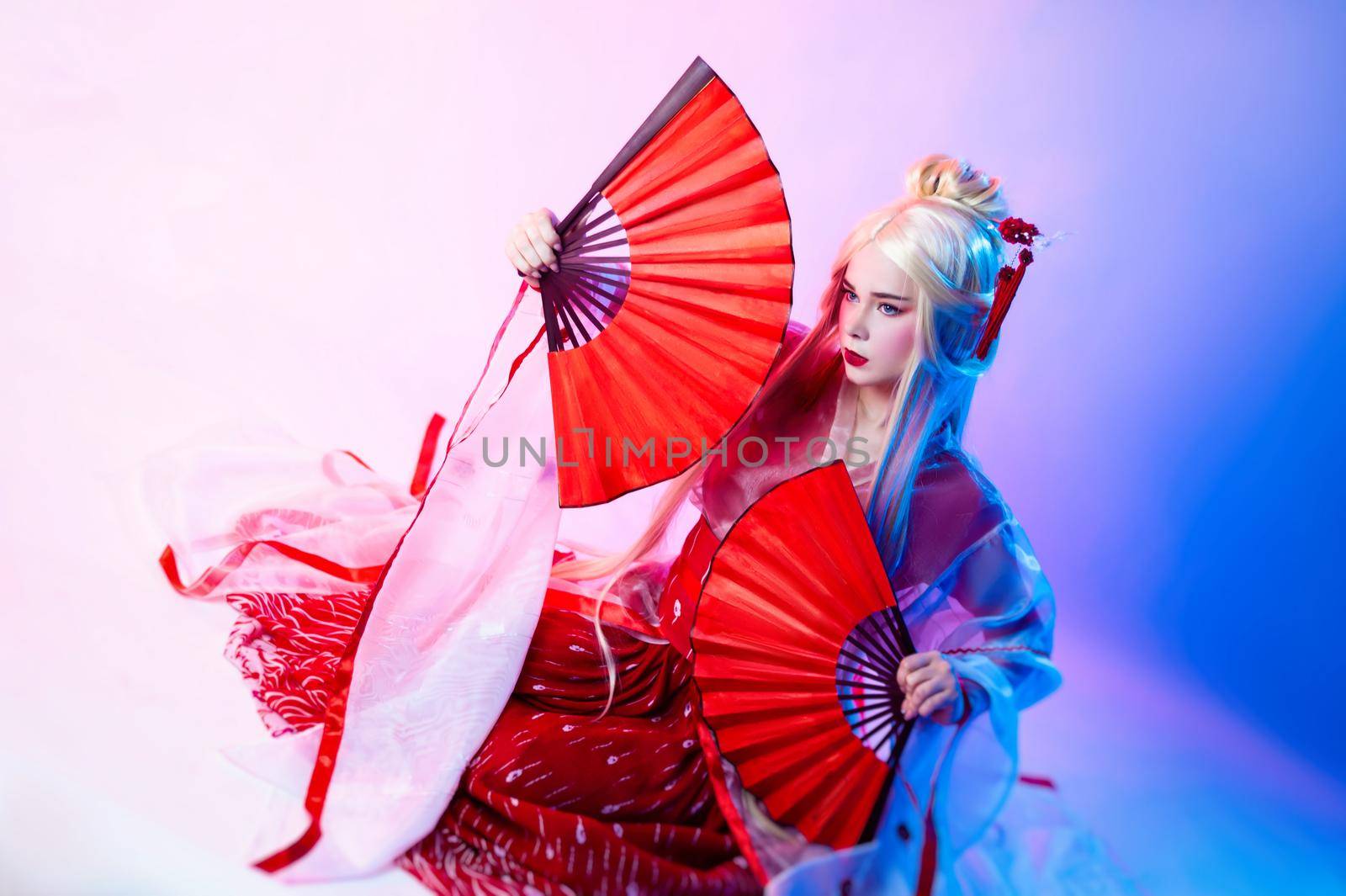 the woman in a geisha costume with fans sits on a white background
