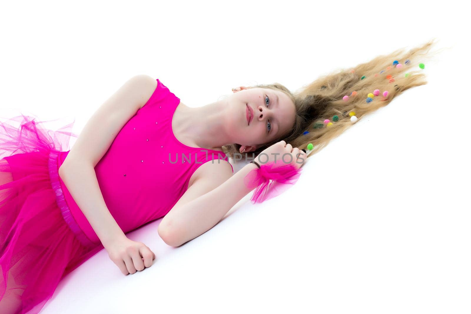 Beautiful girl gymnast schoolgirl lying on the floor with long hair spread out on the floor, in which multicolored confetti are braided. The concept of sport, style and fashion. Isolated on white background.