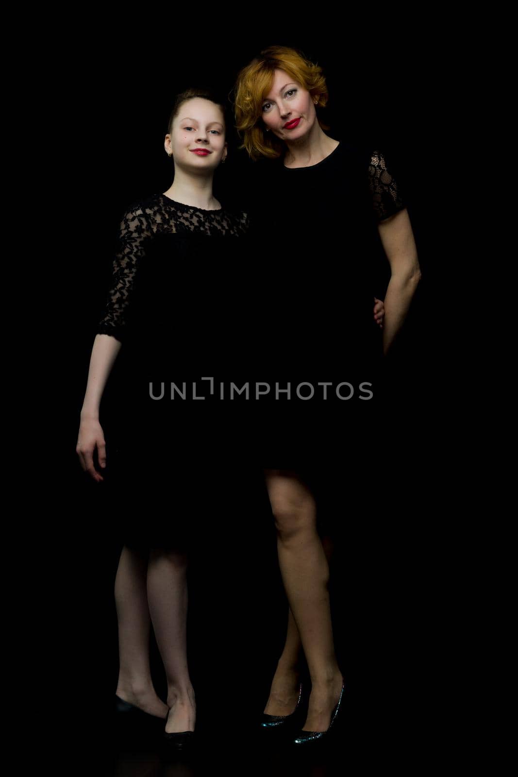 Happy family mom and little daughter, studio portrait.On black background