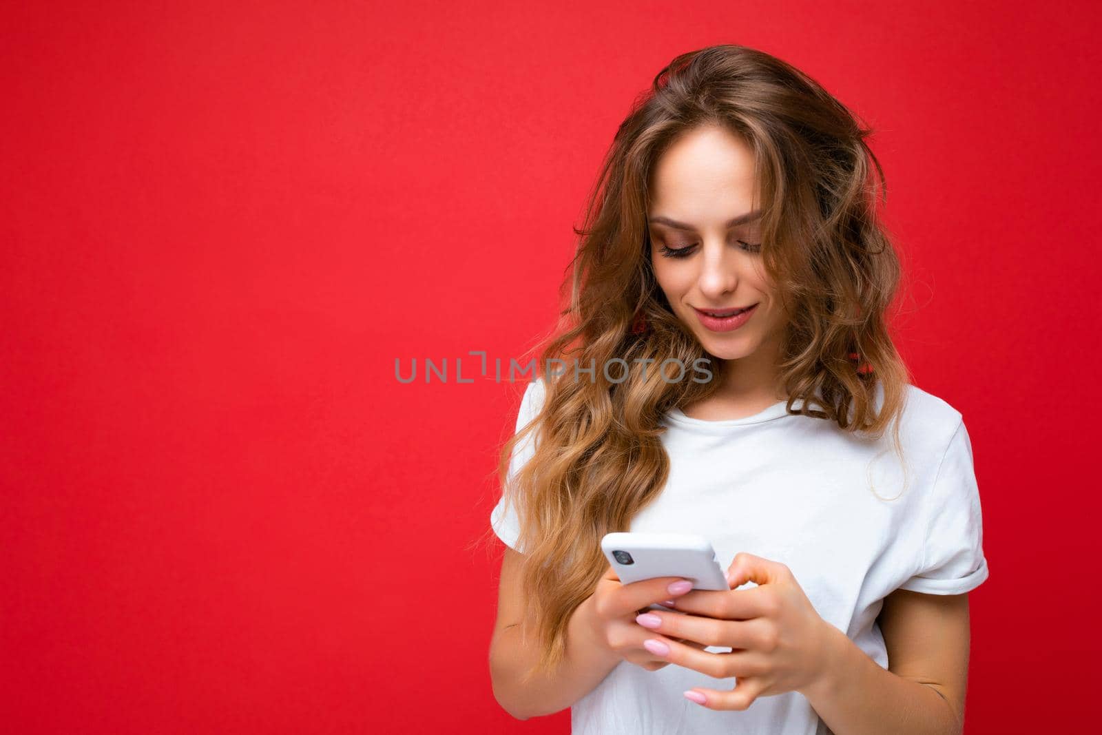 Beautiful young woman wearing casual clothes standing isolated over background surfing on the internet via phone looking at mobile screen.